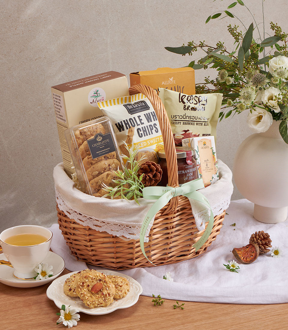 Woven wicker wellness gift basket with coconut waffle, whole wheat chips, almond brownies, strawberry jam, and cookies tied