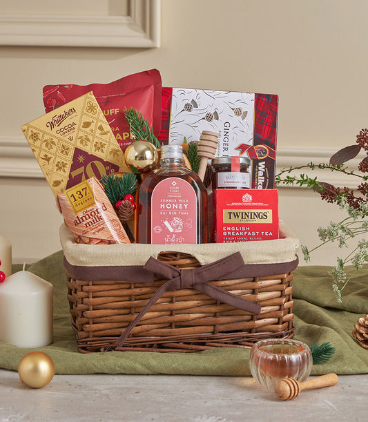 Woven wicker gift basket with honey, tea, almond milk, chocolate and festive decorations for New Year gifting