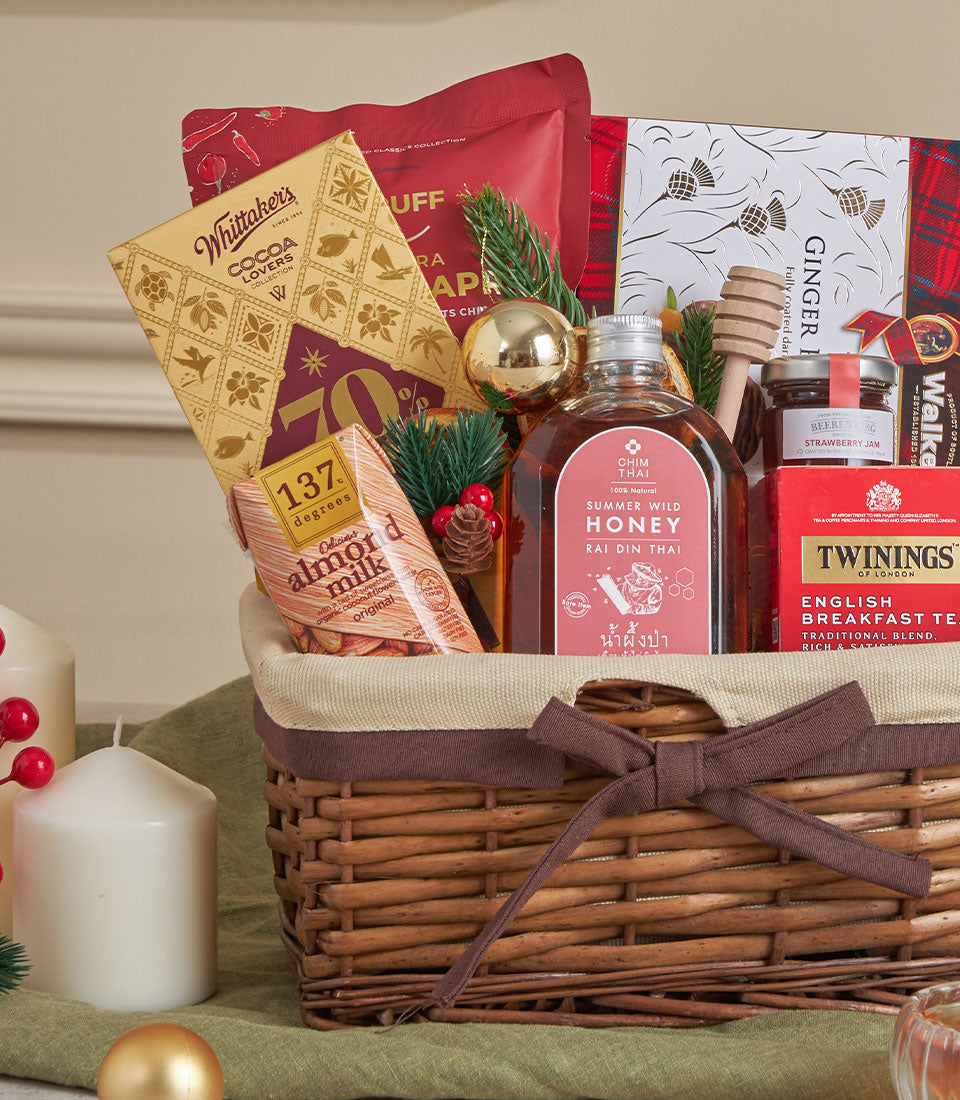 Woven honey and tea comfort gift basket with chocolate, jam, almond milk, and festive gold accents for New Year