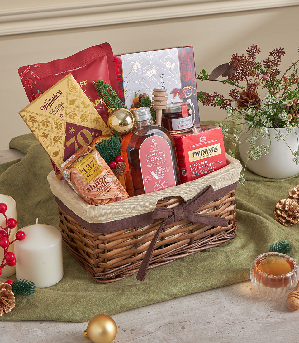 Honey and tea comfort gift basket with woven wicker, gold chocolates, jam, almond milk, and festive red berries for New Year