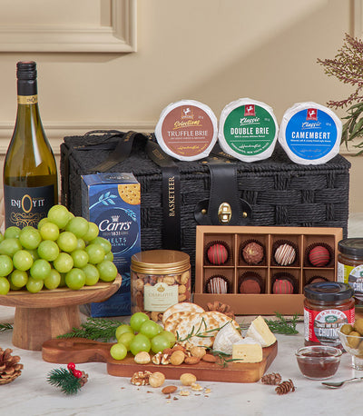 Luxury black woven gourmet basket with Cabernet wine, artisan cheeses, crackers, chocolates, and festive holiday garnish
