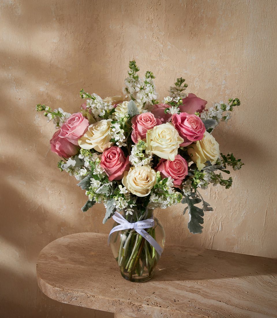 Elegant vase arrangement from Flowers by Basketeer with ivory and pink roses, white stock, and dusty miller. Perfect for flower delivery in Bangkok.