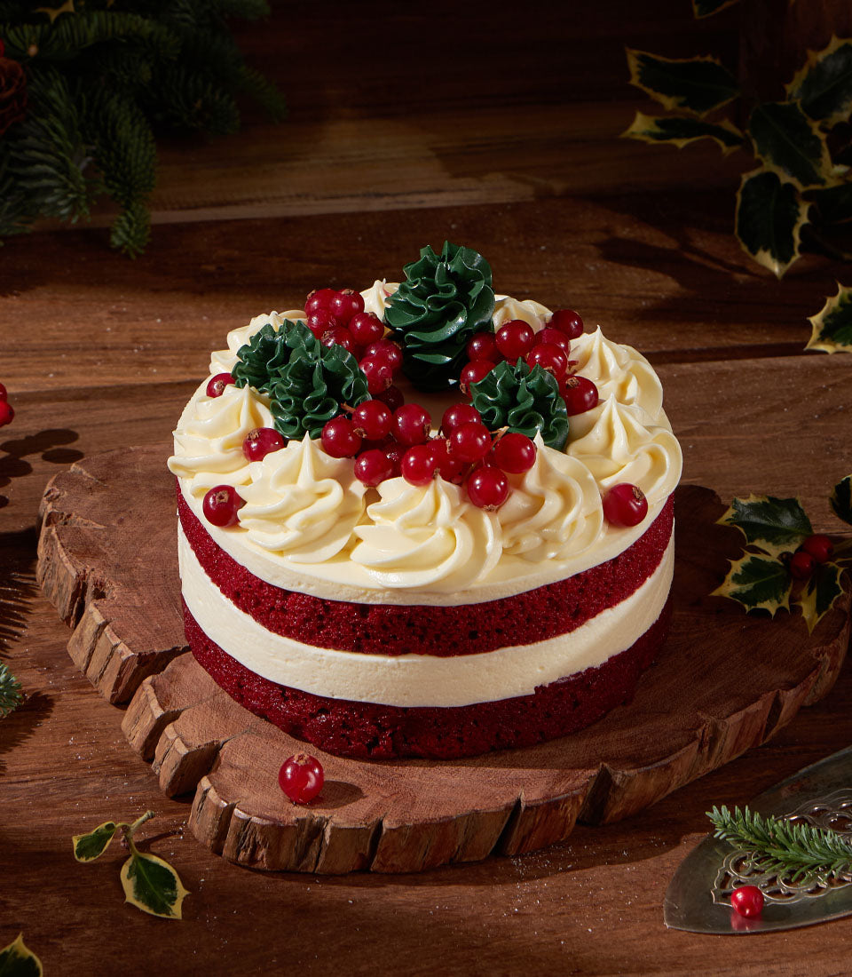 Charlotte Bakery artisan cake, perfect for birthday cake delivery Bangkok. Red velvet with cream cheese frosting, topped with cranberries and buttercream fir trees.