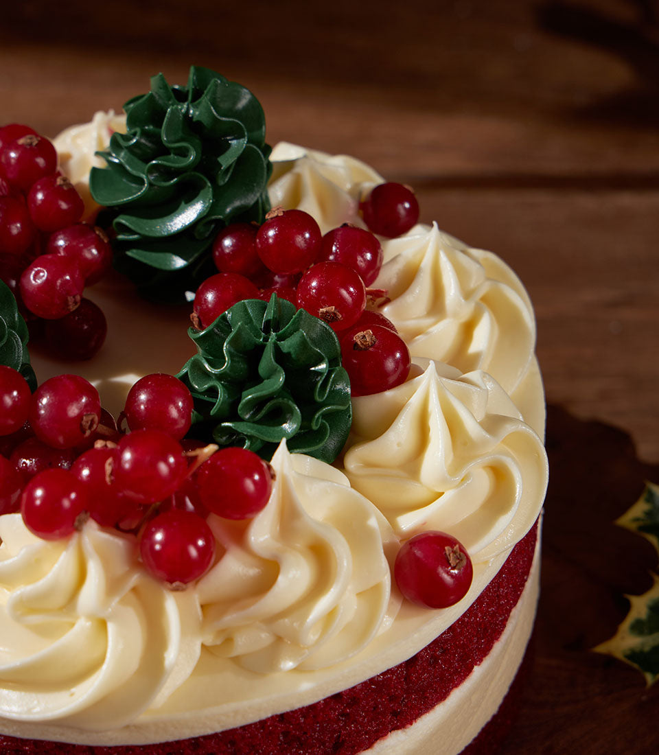 Charlotte Bakery artisan cake: Red velvet pastry with cream cheese frosting, fresh red currants, and green buttercream rosettes. Order a custom cake in Bangkok!