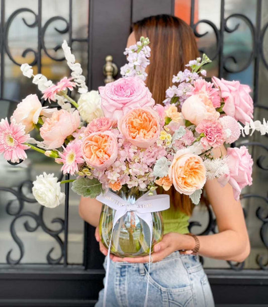 Lush Flowers by Basketeer vase arrangement. Peach and pink roses, gerbera daisies, and hydrangea create an elegant premium flower delivery Bangkok.