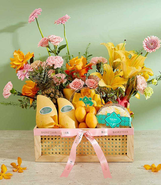 Premium tropical fruit basket with pink roses, gerberas, lilies, mangoes, pineapple, and fresh flowers