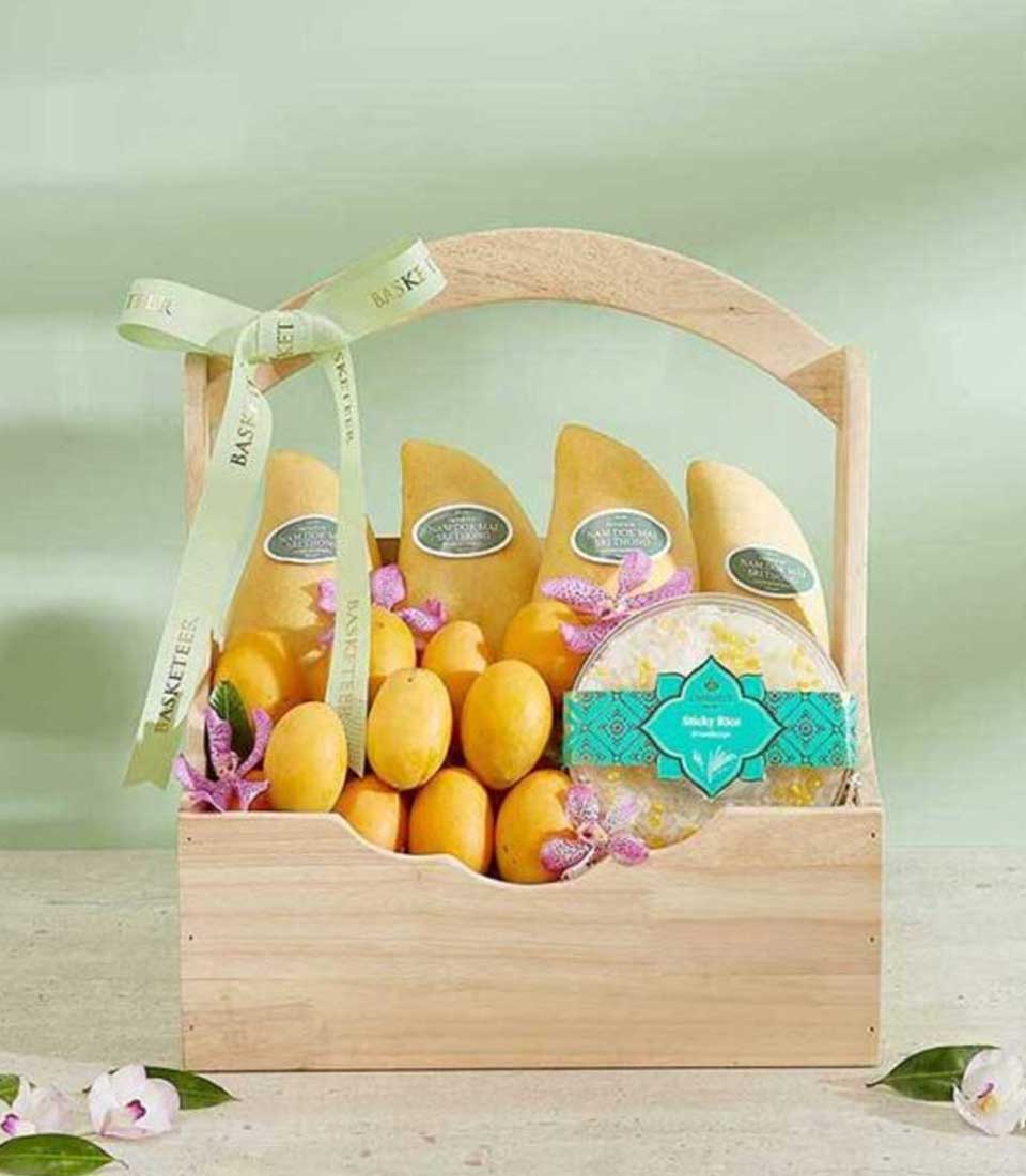 Premium wooden gift basket filled with golden mangoes, sticky rice dessert, and fresh orchid blossoms