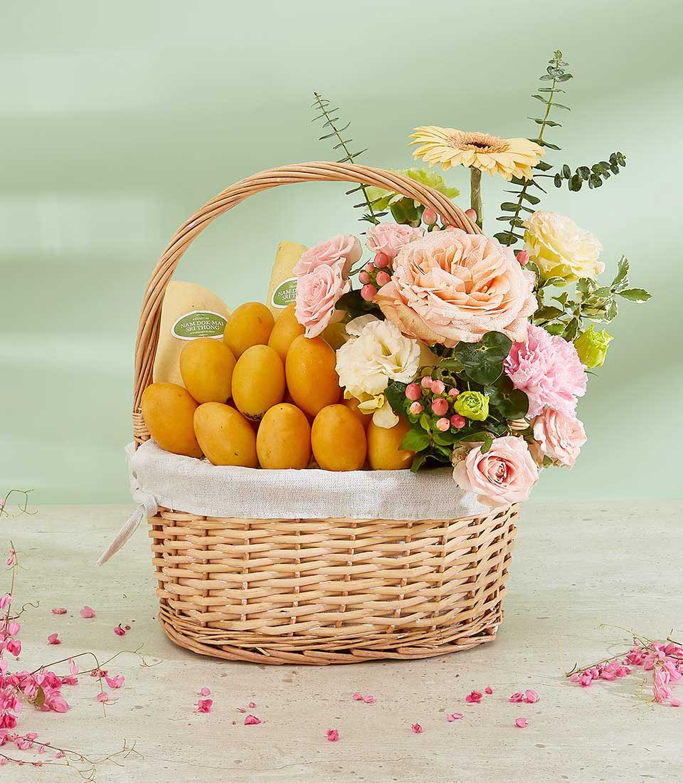 Luxury Thai mango and rose gift basket with peach roses, pink carnations, and fresh tropical fruit in woven wicker