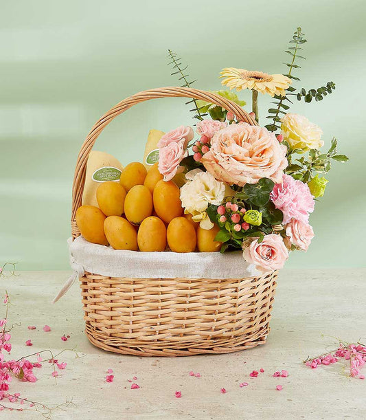Luxury Thai mango and rose gift basket with peach roses, pink carnations, and fresh tropical fruit in woven wicker