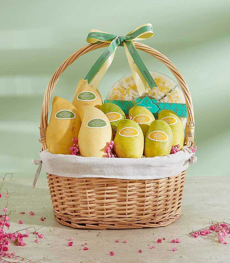 Woven gift basket with Nam Dok Mai and Oak Rong mangoes, sticky rice dessert, and fresh pink flowers
