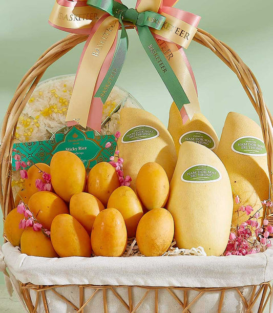 Woven wicker basket filled with Thai Nam Dok Mai mangoes, sticky rice, and pink florals with ribbon bow