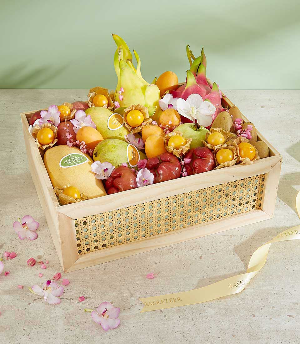 Luxurious wooden crate filled with fresh Thai tropical fruits, mangoes, guavas, and dragon fruit with orchids