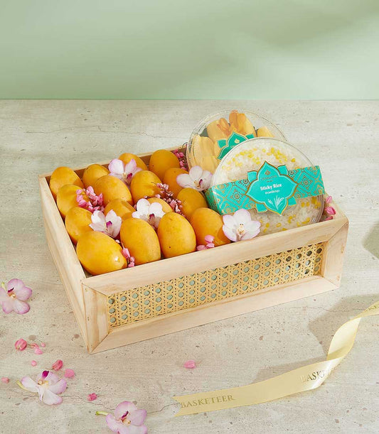 Wooden gift basket with fresh Thai mangoes, orchids, sticky rice, and mango slices