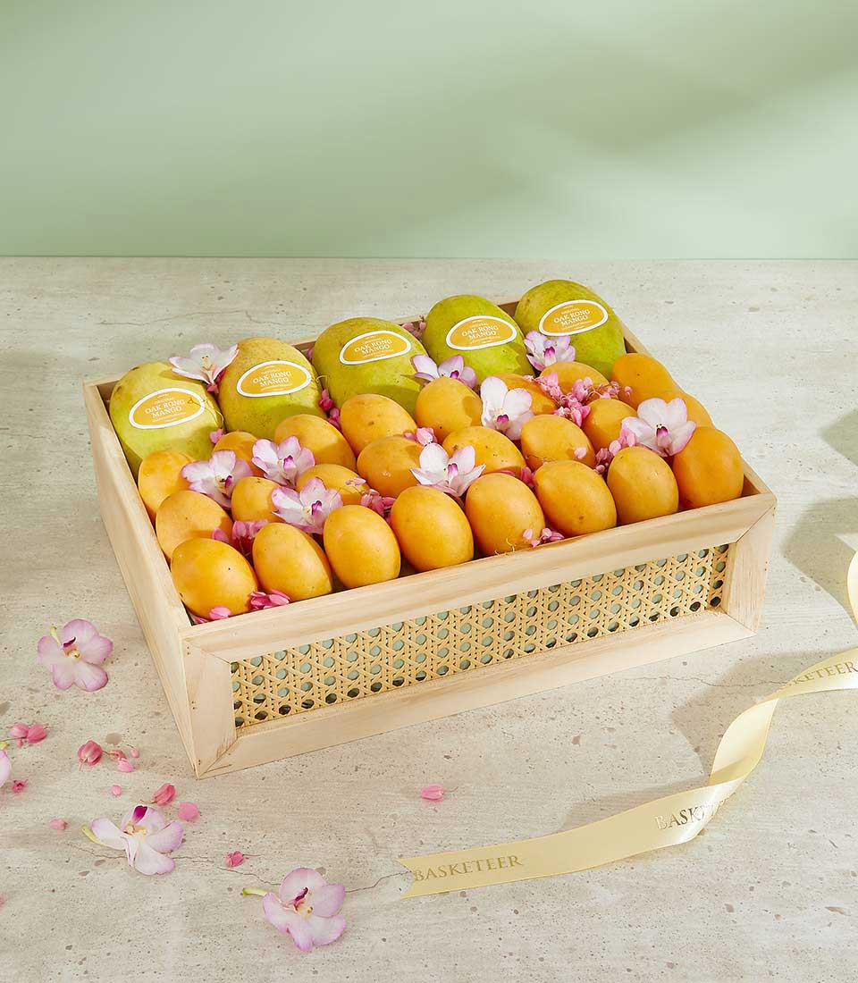 Wooden gift box with Thai mangoes, apricots, and pink orchid blossoms, luxury tropical fruit hamper