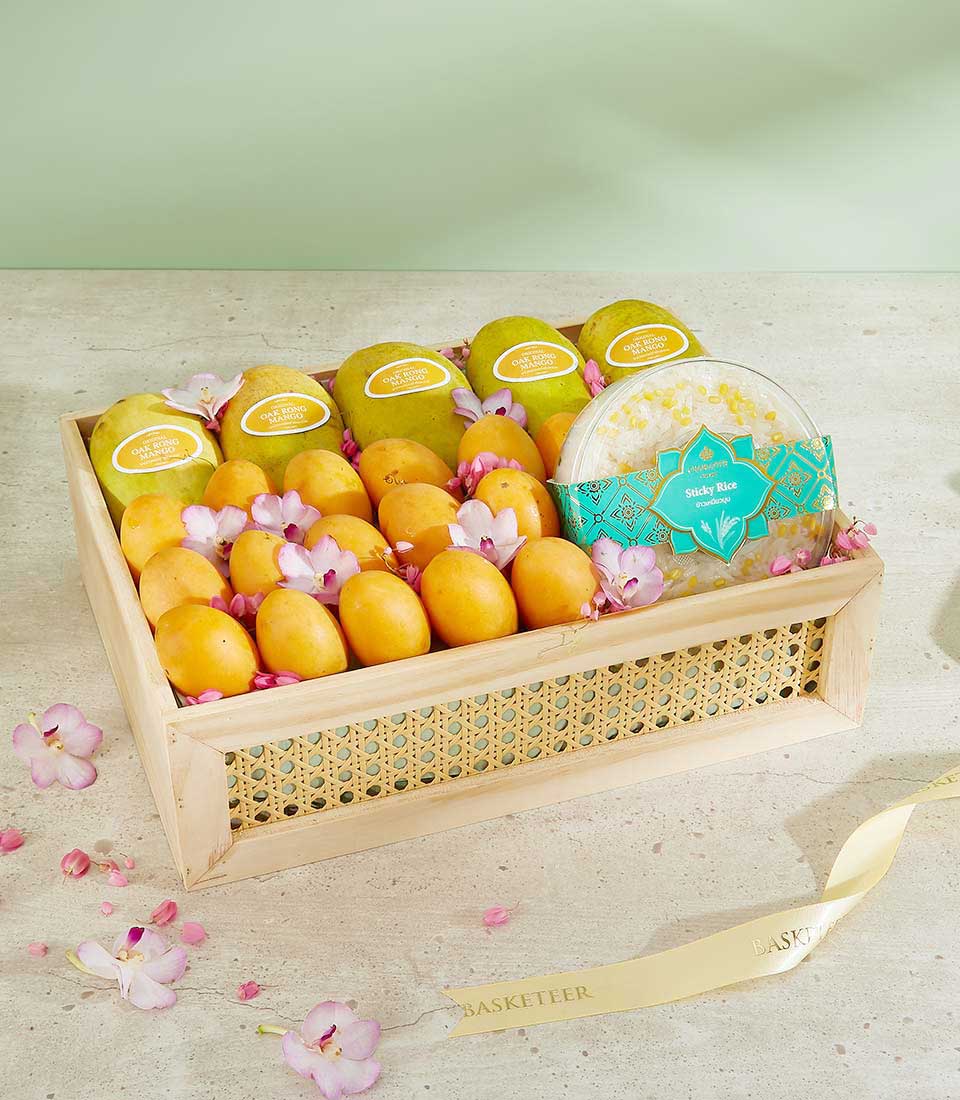 Premium Thai tropical fruit gift basket with mangoes, plums, sticky rice, and orchid flowers in woven cane presentation