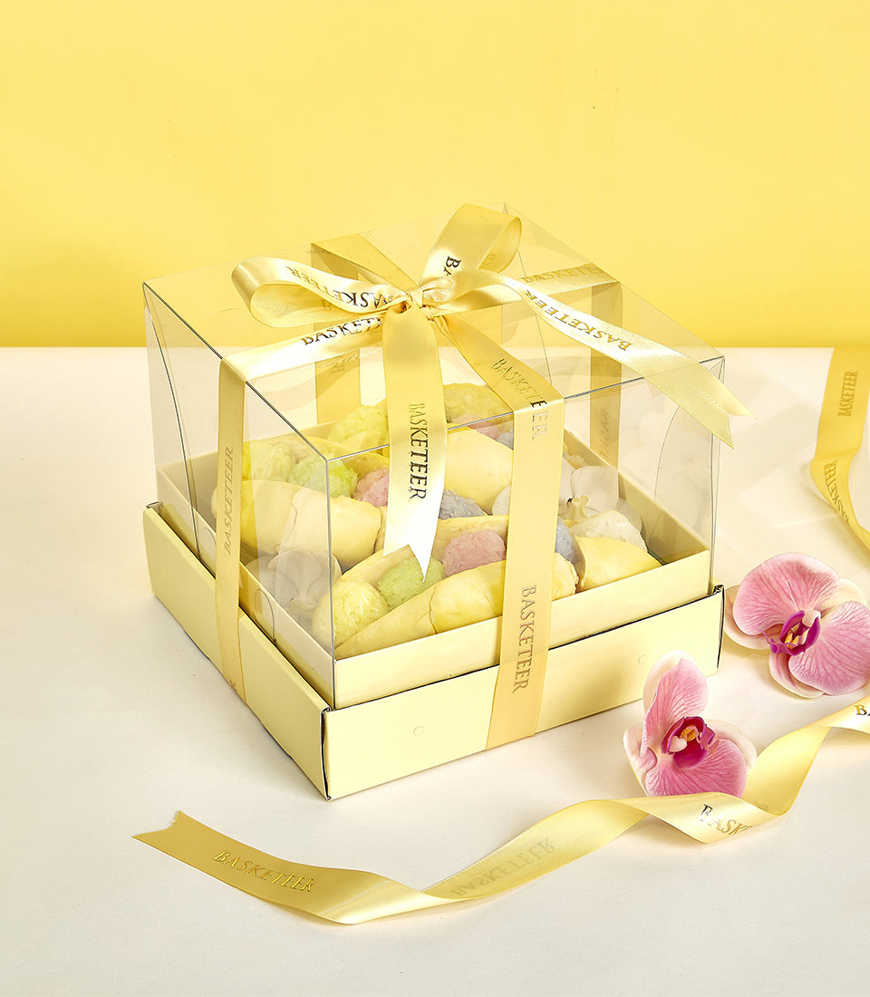 Vibrant monthong durian gift box with pastel confections and pink orchids, tied with gold Basketeer ribbon