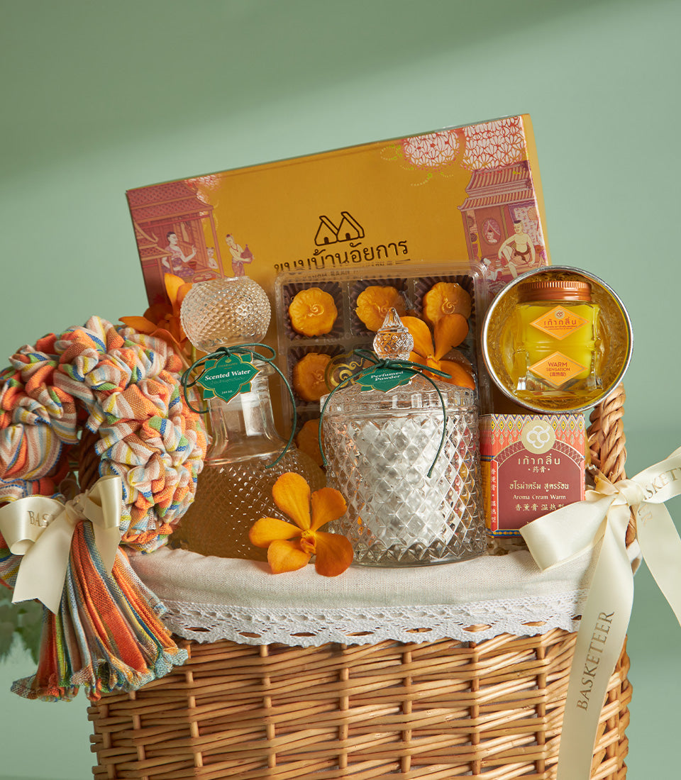 Woven wicker heritage gift basket with Thai-inspired yellow box, scented water, perfumed powder, orchid, and golden jars for