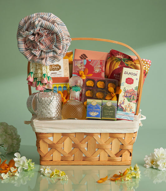 Woven wood gift basket with layered fabric flowers, Thai garland, coconut treats, and gourmet goods for Songkran celebration