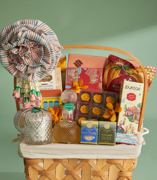 Woven wicker gift basket filled with Thai gourmet treats, coconut chocolate, banana snacks, aroma cream, scented water, and