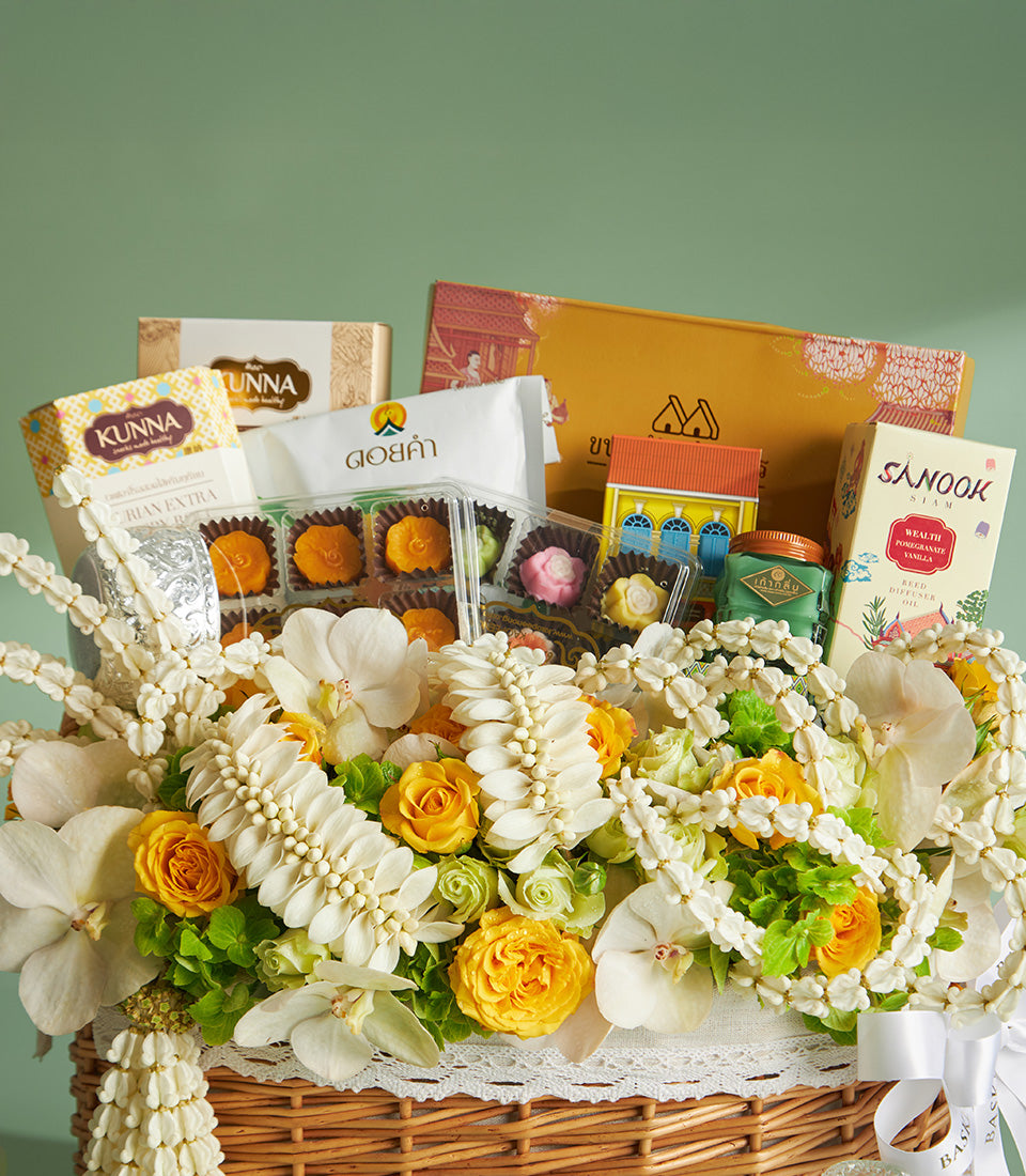 Woven wicker Songkran blessing basket with white orchids, yellow roses, and Thai treats for Thai New Year celebrations