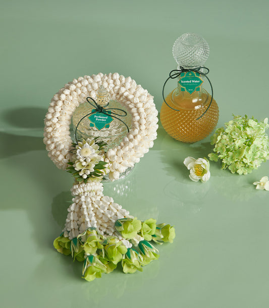 Songkran garland gift set with jasmine phuang malai, scented water, and perfumed powder on green surface