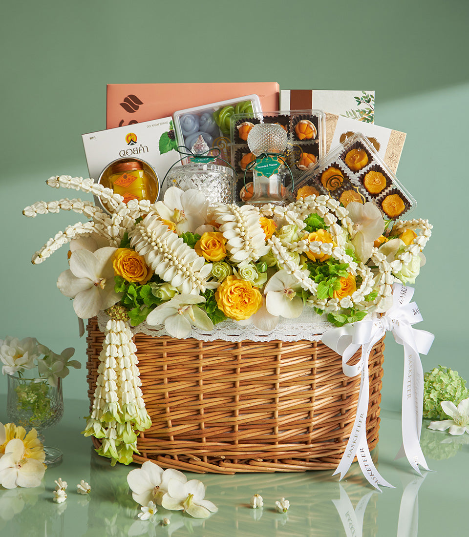 Woven wicker gift basket with white orchids, yellow roses, Thai garlands, gourmet treats, and Songkran gifts for Thai New