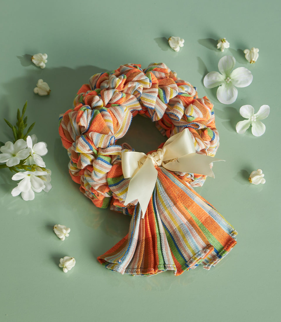 Colorful striped fabric wreath with cream satin bow and white jasmine flowers for Songkran celebration