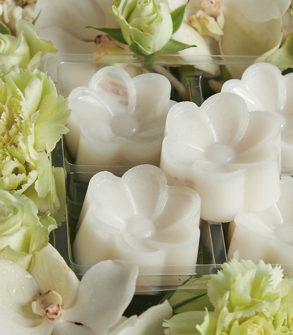 White flower-shaped sweets in clear box with fresh orchids and green carnations for Songkran celebration