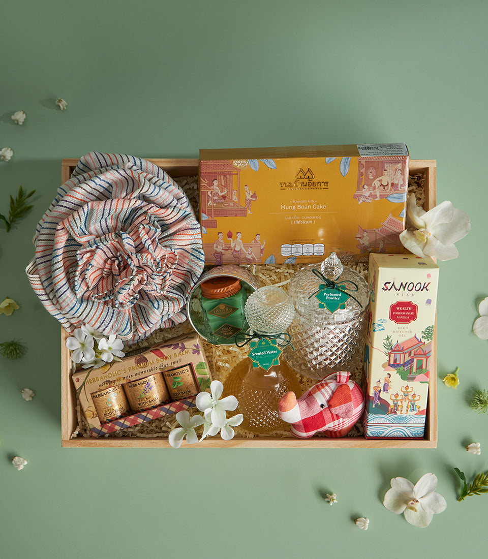 Thai Songkran gift box with mung bean cake, reed diffuser, body balm, and traditional woven scarf on light green background