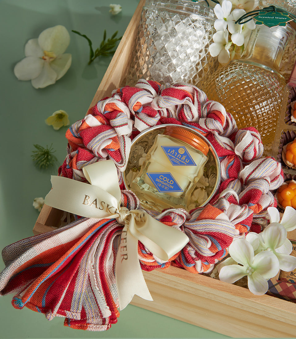 Sacred Songkran Thai treats gift box with cold sensation jar, bottled goods, and pumpkin-shaped snacks in wooden crate