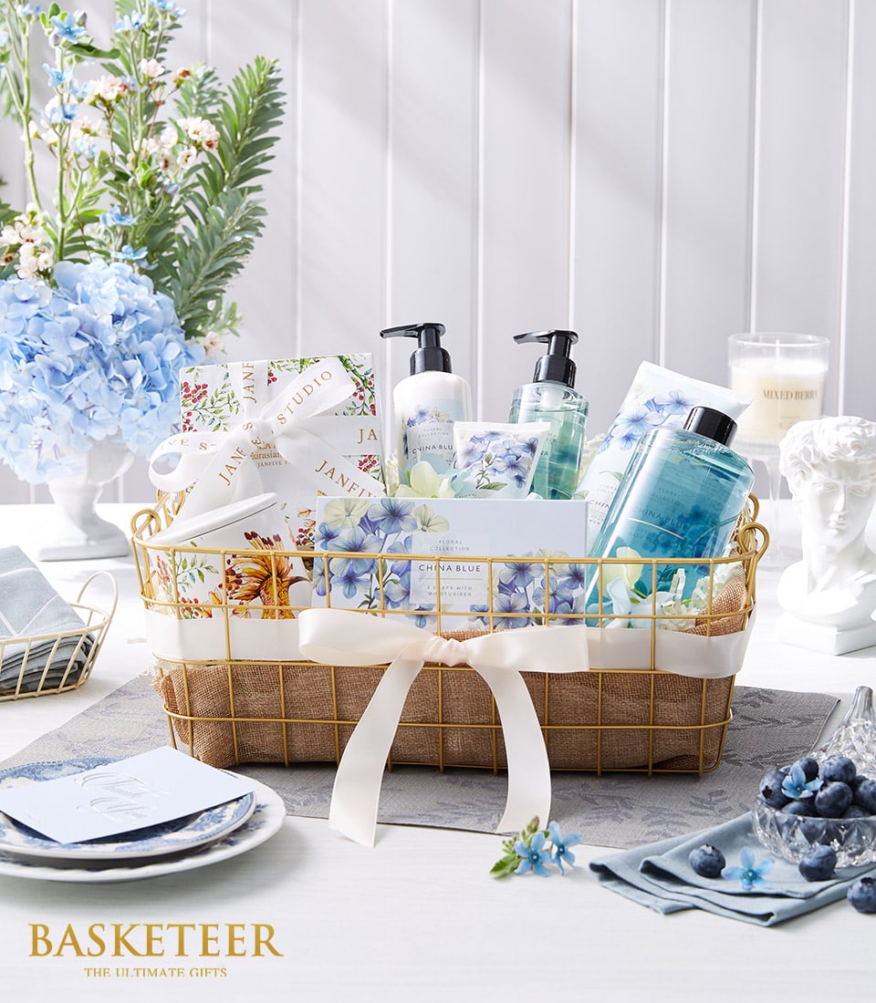 Luxury spa gift basket with blue floral bath products, gold wire design, and cream ribbon bow