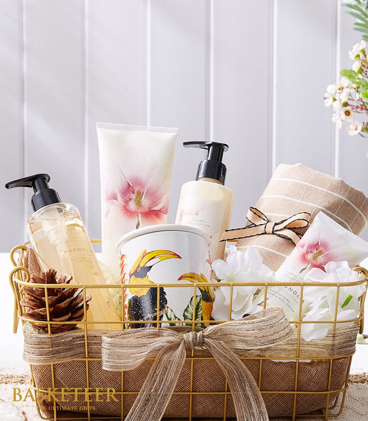 Gold wire mesh spa gift basket with magnolia hand wash, moisturising creams, ceramic toucan candle, and striped towel