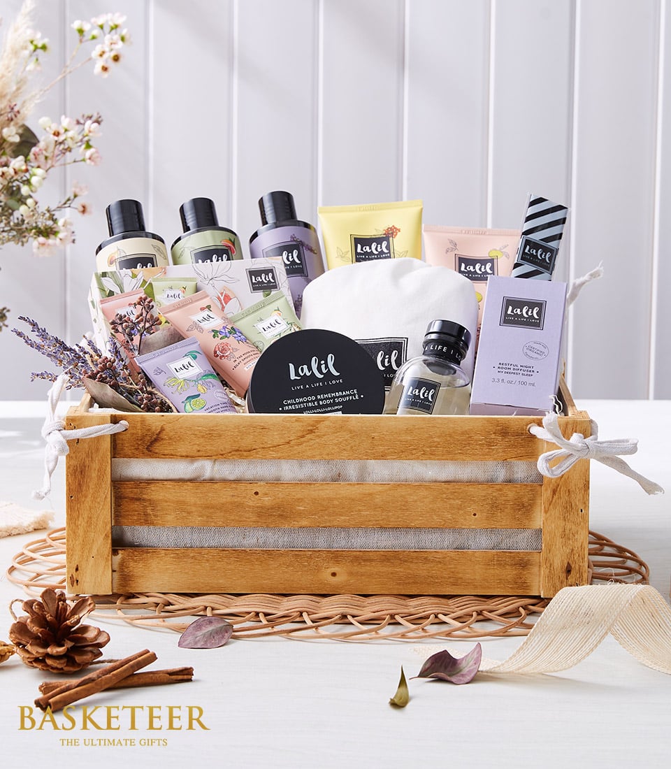 Luxury spa gift basket with pastel bath and body products, lavender, and soft linens in rustic wooden crate