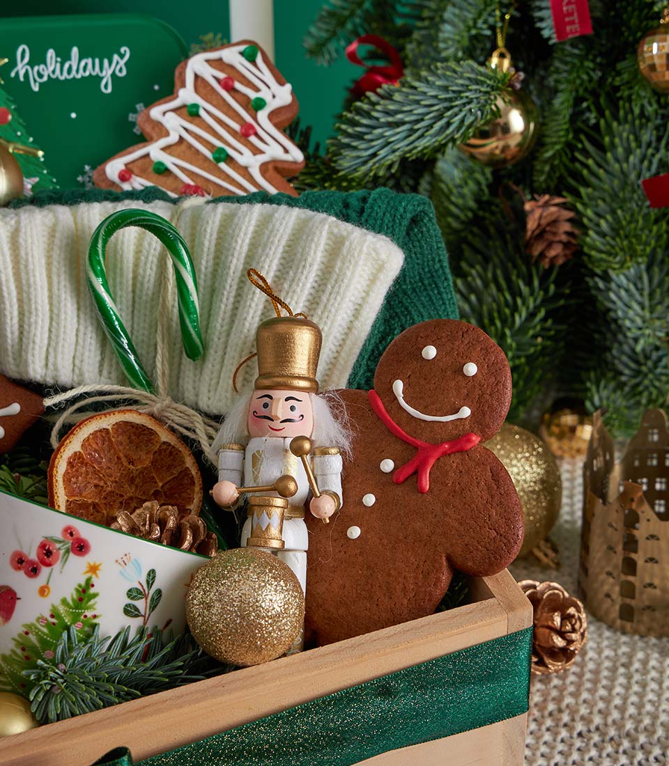 Festive Christmas gift basket with gingerbread cookies, nutcracker ornament, and holiday treats in wooden box with green
