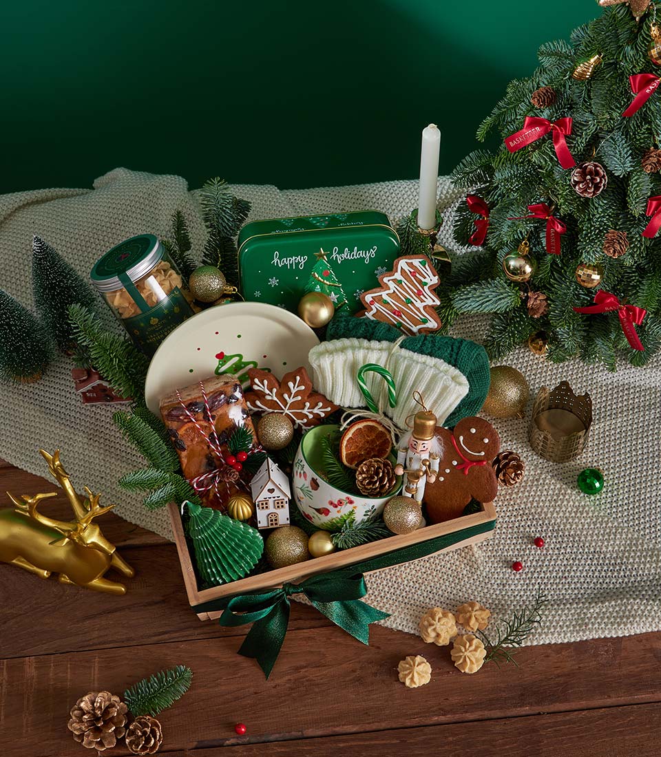 Festive Christmas gift basket with gingerbread cookies, fruitcake, mug, and holiday decorations in wooden tray