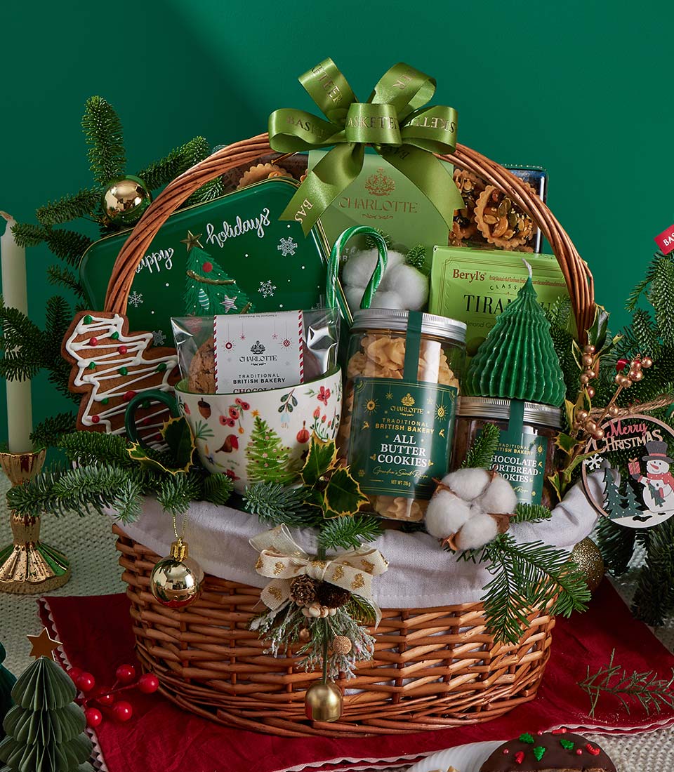 Woven wicker Christmas gift basket with festive green bow, filled with artisan British bakery cookies, chocolates, ceramic