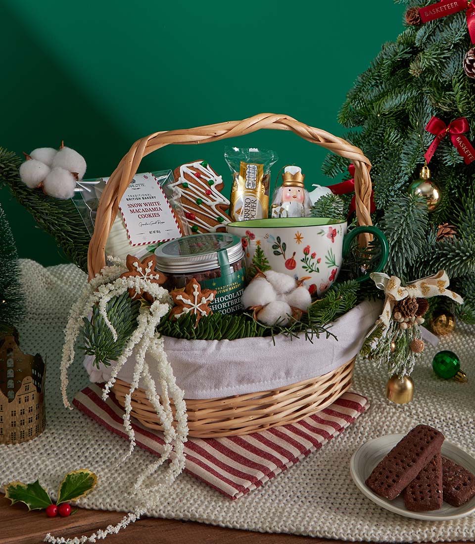 Wicker Christmas gift basket with shortbread cookies, gingerbread, festive mug, and Ferrero Rocher chocolates