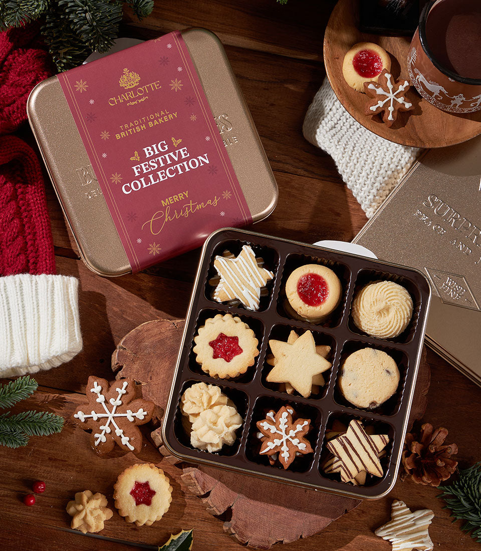 Festive Christmas cookie collection in gold tin with assorted decorated shortbreads, gingerbread, and jam-filled treats