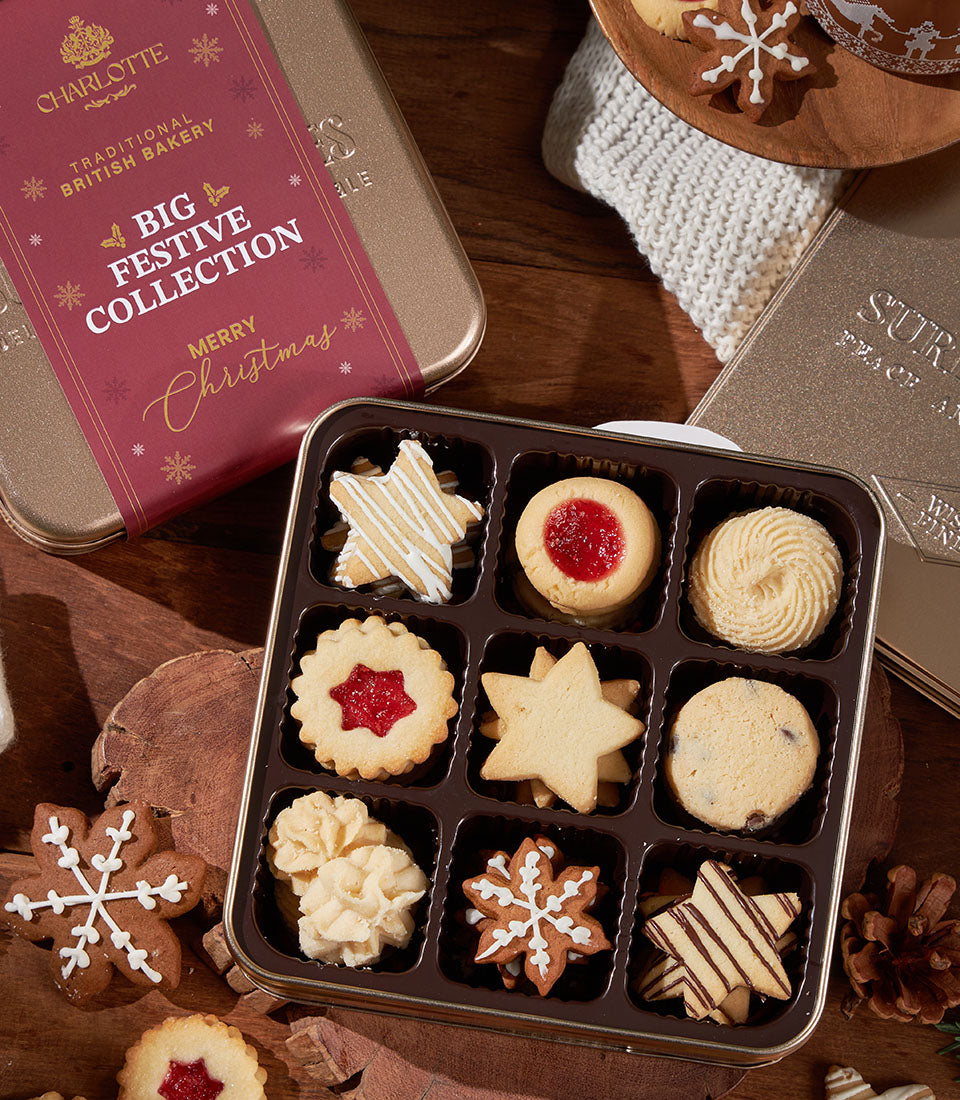Festive British bakery cookie collection in gold tin with star, gingerbread, and jam-filled varieties for Christmas gifting