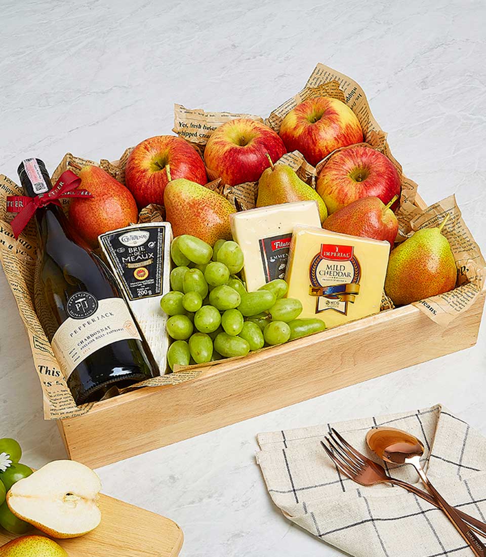 Wooden gift crate with white wine, artisan cheeses, fresh fruit and serving accessories