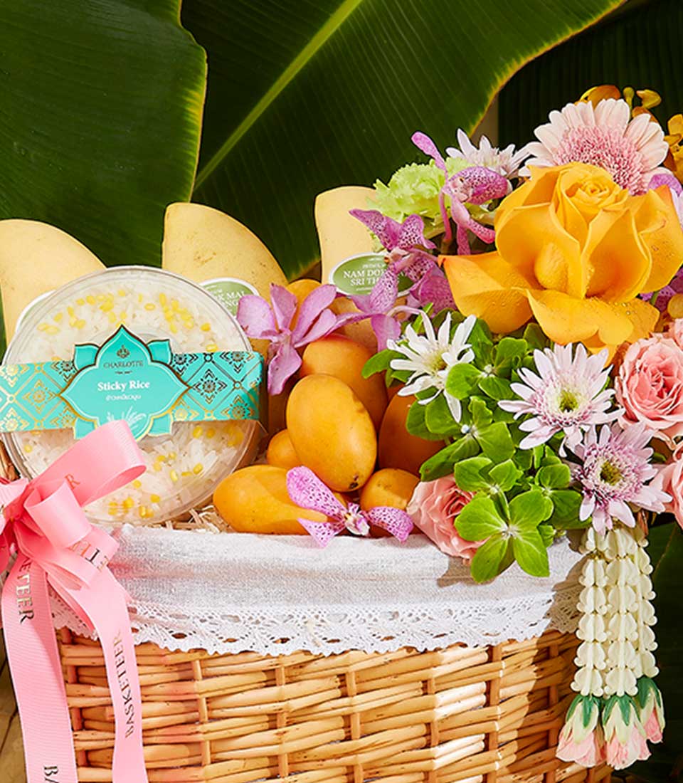 Vibrant Thai New Year gift basket with mangoes, sticky rice, yellow roses, and orchid arrangement