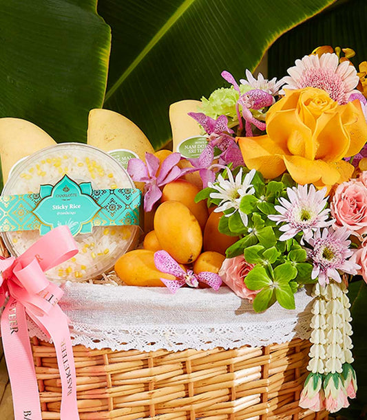 Vibrant Thai New Year gift basket with mangoes, sticky rice, yellow roses, and orchid arrangement