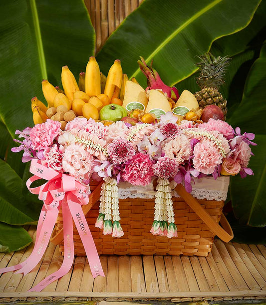 Tropical Songkran fruit basket with fresh mangoes, pineapple, dragon fruit, and vibrant pink flowers in handwoven basket