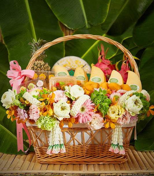 Woven wicker gift basket with Thai fruits, sticky rice, and fresh white, pink, and yellow flowers for Songkran celebration