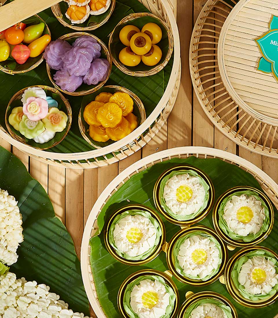 Traditional Thai desserts gift set with colorful candies and lotus-shaped kanom ar-lua on bamboo trays for Songkran