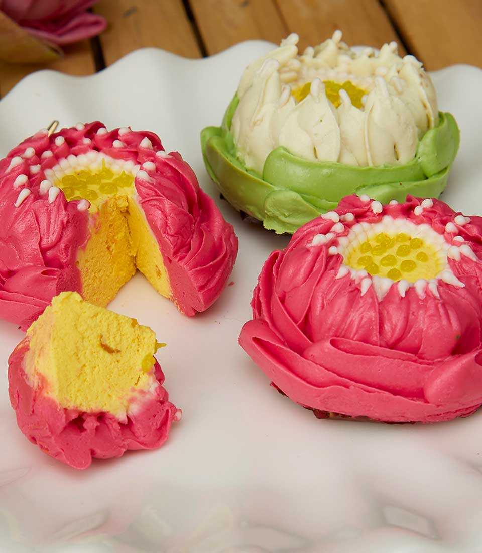 Lotus-shaped Thai desserts in pink and white with yellow centers on scalloped plate, Songkran celebration gift set