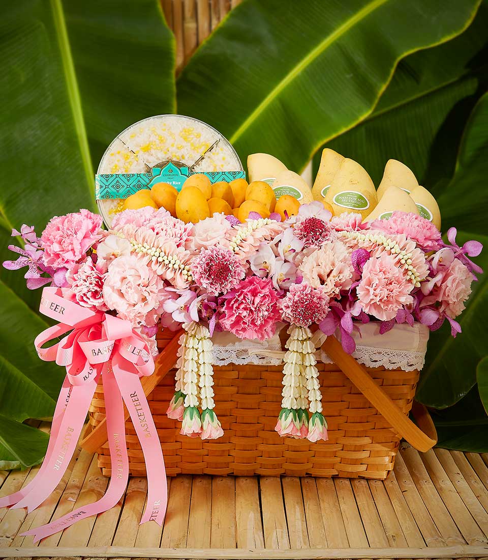 Thai floral fruit gift basket with pink orchids, carnations, mangoes, and sticky rice for Songkran celebration