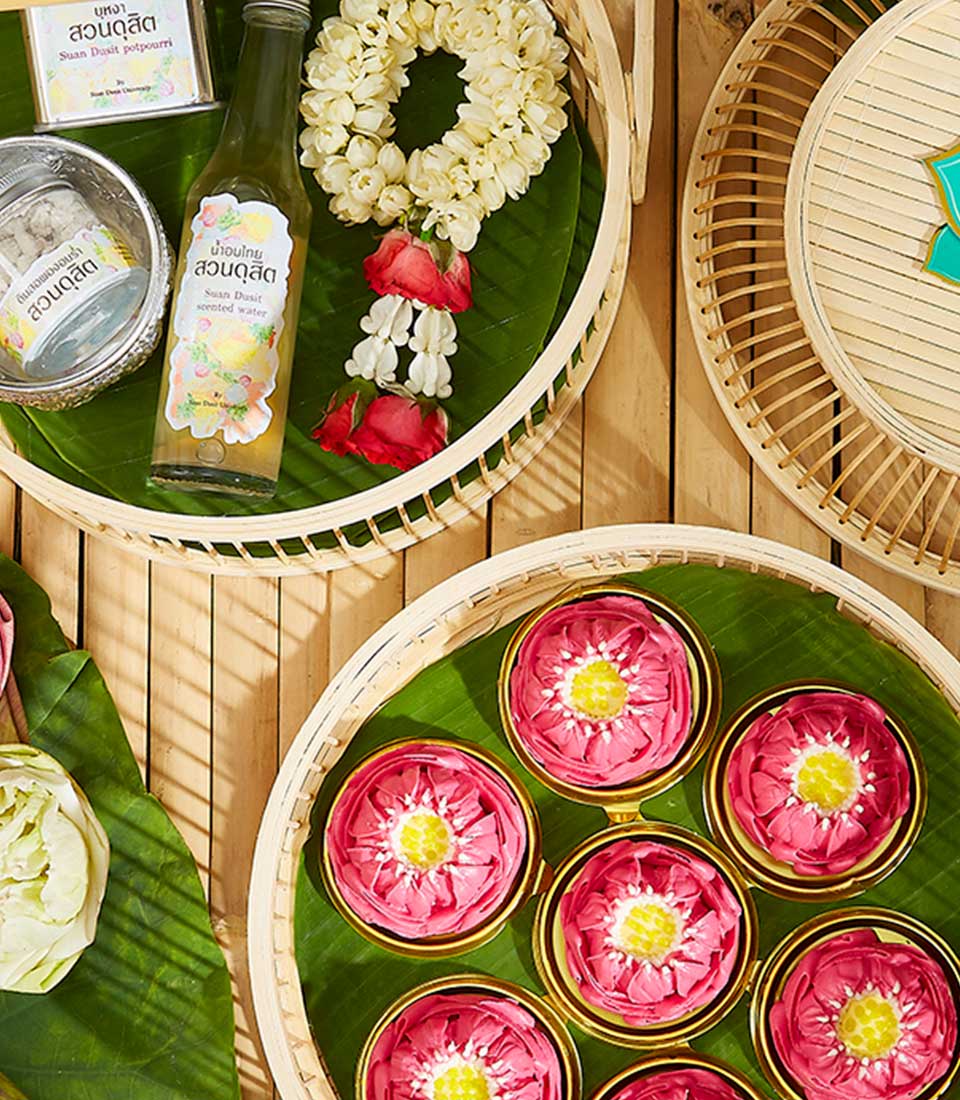 Thai New Year Songkran blessing set with jasmine garland, scented waters, and lotus-shaped kanom ar-lua treats in woven
