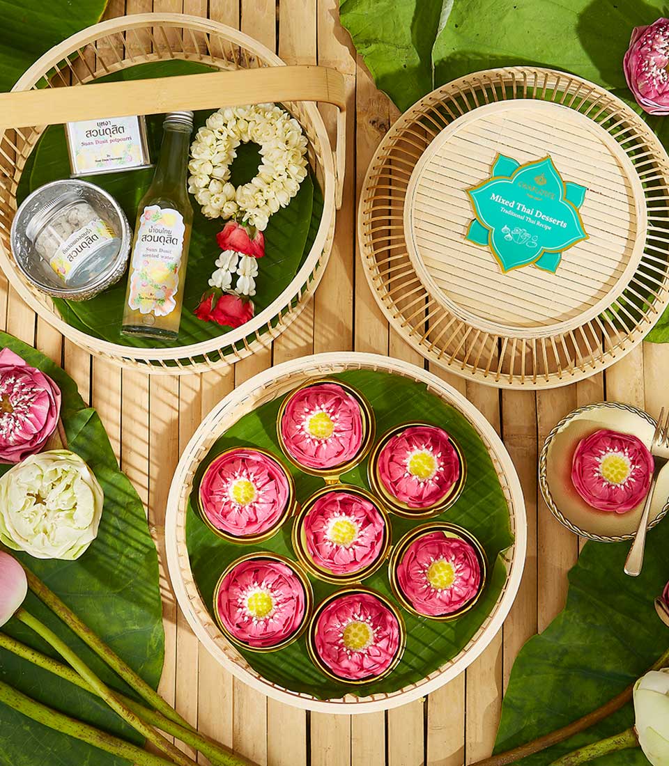 Thai New Year Songkran blessing set with jasmine garland, scented water, traditional kanom desserts, and fresh lotus flowers