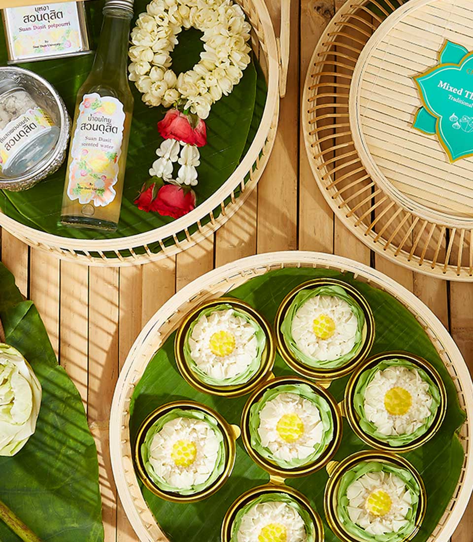 Thai New Year gift set with fragrant water, potpourri, white lotus kanom ar-lua, and fresh flower on banana leaf